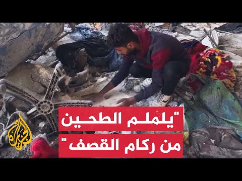 فلسطيني يجمع الدقيق المتسرب من أرضية أحد مخازن الأونروا بعد قصفه